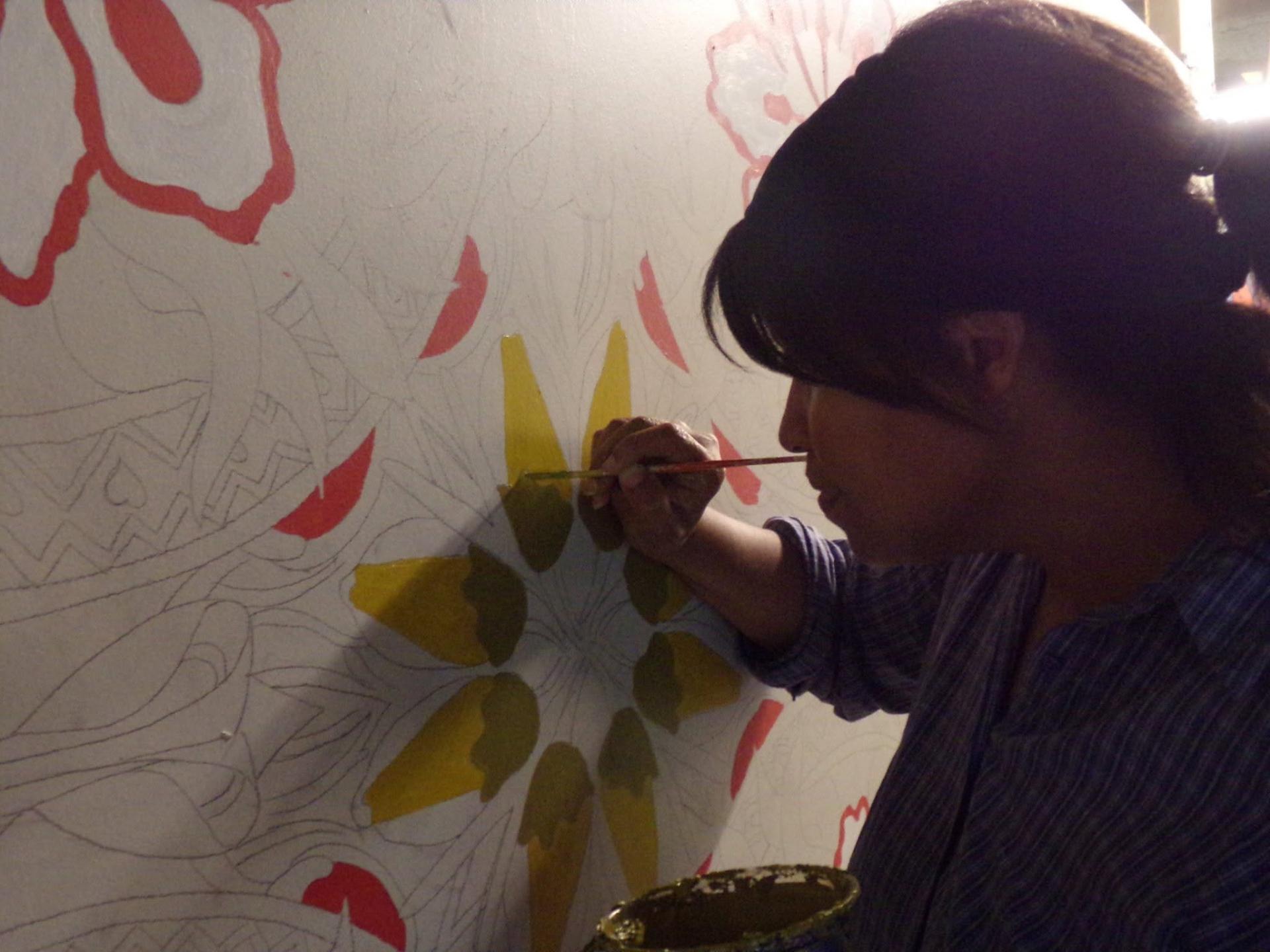 Sheena Garcia painting a floral panel for the Spring Garden Bridge mural